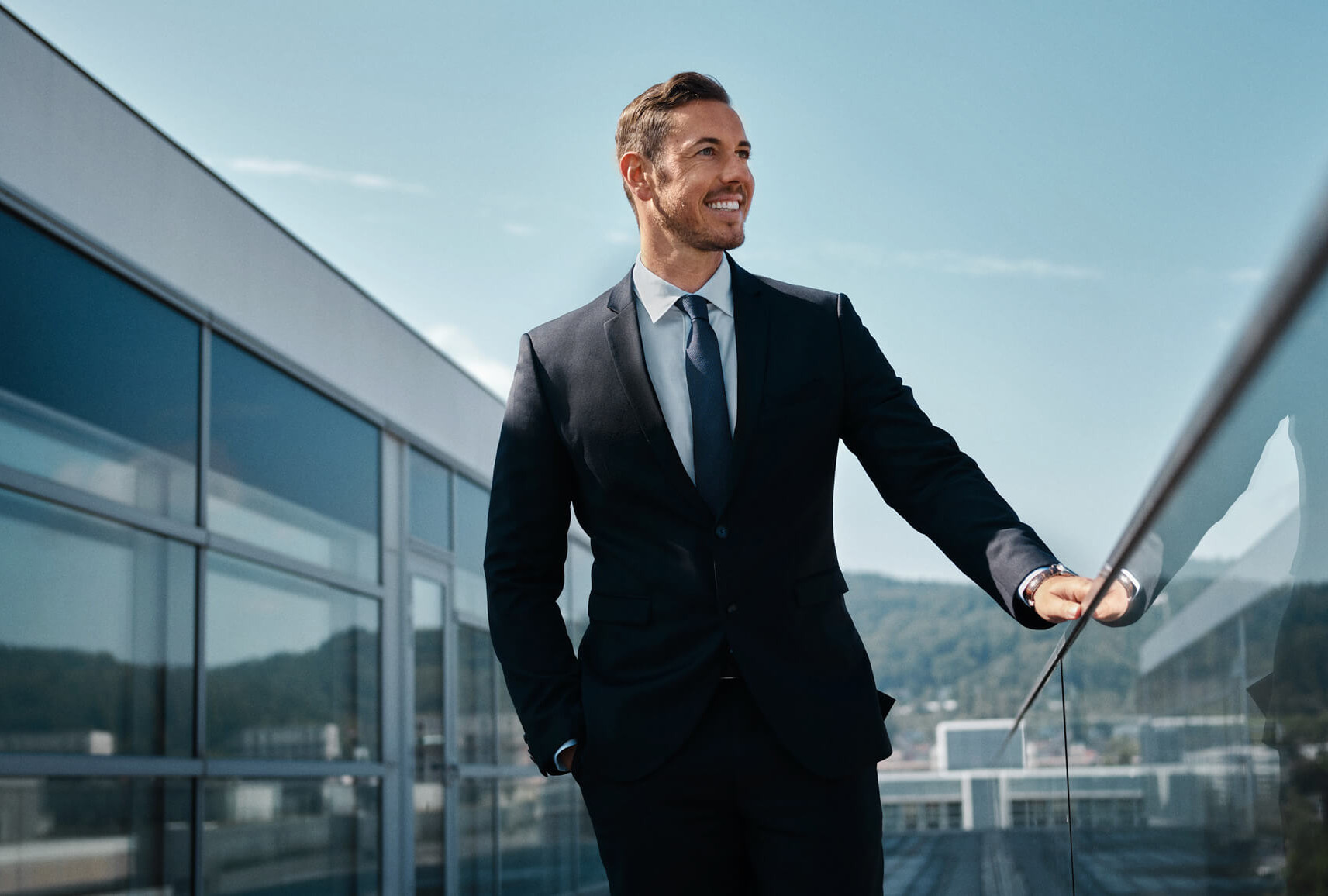 Makler auf dem Balkon schaut an der Kamera vorbei in die Ferne